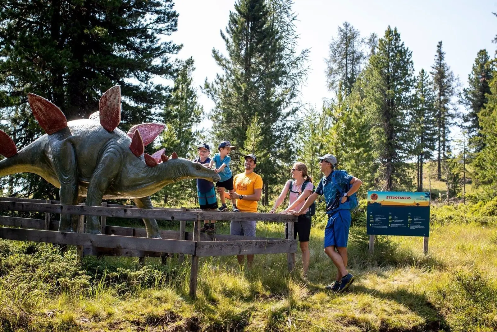 Gezin met kinderen bij een levensgrote stegosaurus in het Dinowald op de Kreischberg